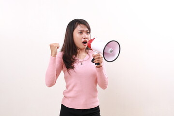 Angry young asian girl standing shouting using megaphone to sideways. Isolated on white background