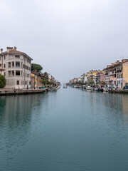 Obraz premium Grado, Italy - January 01th, 2024: View of the Mandracchio port in Grado, Italy. Foggy day and little visibility. Fishing boat leaving for a fishing trip.