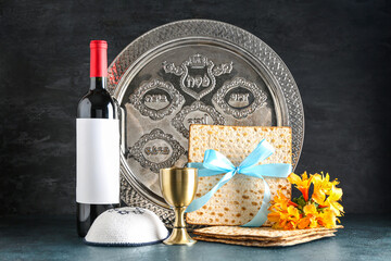 Bottle of wine, cup, Passover Seder plate and flatbread matza on dark background