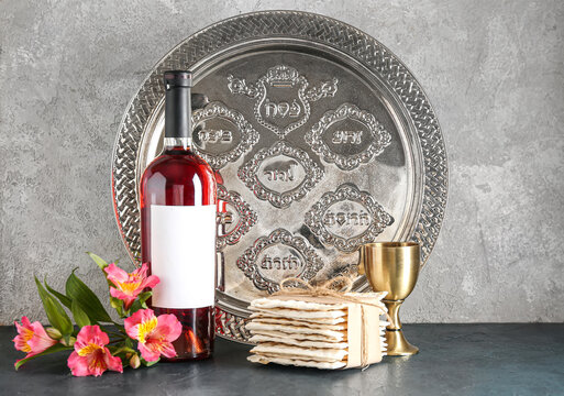 Bottle of wine, cup, Passover Seder plate, flatbread matza and alstroemeria flowers on grunge background