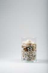 Seashells and starfish candles with stones in a glass on light background