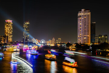 Night light landscape along the Chao Praya River, having some boats come to celebrate the New Year eve on the Asiatique landmark side in Bangkok city, Thailand.