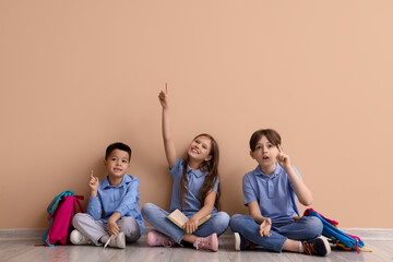 Little pupils pointing at something near beige wall