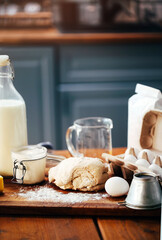 Assorted ingredients for pastry preparation placed on wooden chopping board on table in kitchen