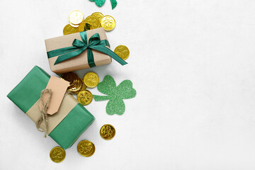 Gifts with paper clovers and golden coins on light background. St. Patrick's Day celebration