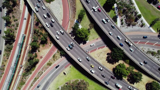 Top down view at a busy traffic junction in Perth, Australia. Aerial view of cars and metro trains smoothly move around, depicting how the city is designed and how people get around