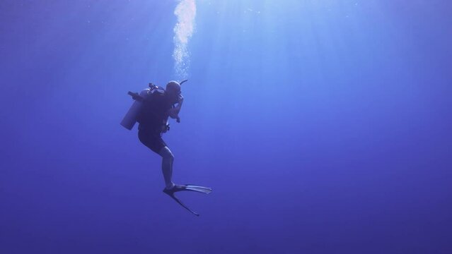 still view of a scuba diver student trying to do Frenzel equalize pressure in the head by squishing the nose to go down deeper into the ocean blue sea salt water underwater world during day time