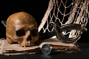 Human skull with sword, old manuscripts, net and compass on black background
