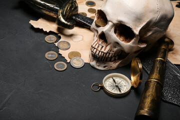 Human skull with sword, spyglass, compass and coins on black background