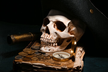 Human skull with old manuscripts, travel equipment, pirate hat and coins on black background