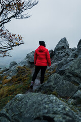 Frau mit roter Jacke in den Bergen genießt den Ausblick