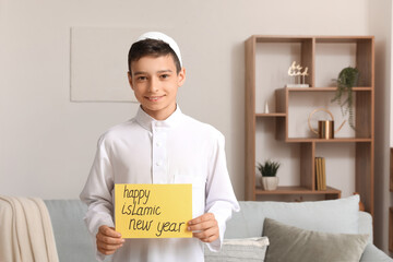 Little Muslim boy with greeting card for Islamic New Year at home