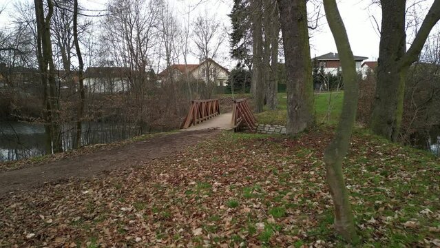 pedestrian bridge over a small gorge and a stream. it consists of two steel crossbeams. as the surface and railing of the bridge is made of brown painted planks. is long and narrow. in the wild