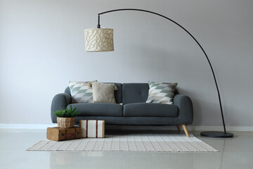Grey sofa with soft cushions near white wall - obrazy, fototapety, plakaty