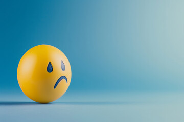 Blue Monday concept. Yellow sad emoji face on light blue background - obrazy, fototapety, plakaty