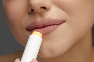Closeup Of Female Face With Soft Skin Putting Lip Protector Lipstick On. Lips Skin Care. Beautiful Woman Face With Sexy Full Lips Applying Hygienic Lip Balm.