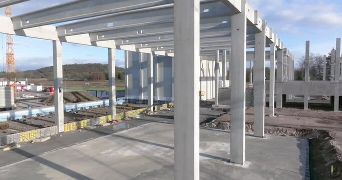 Drone video of a construction site of an industrial building with columns and beams and a heavy-duty crane