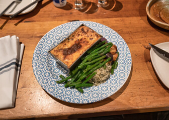 Lasagna cheese baked with green bean and rice served on ceramic plate in restaurant
