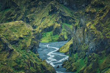 Landscape of lush rugged volcanic mountain valley with river flowing in summer on Icelandic highlands at Thorsmork