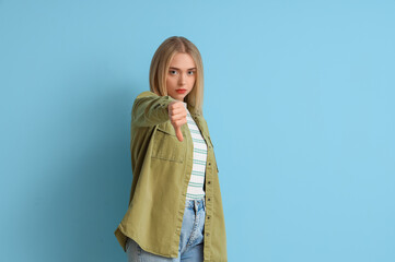 Young woman showing dislike on blue background