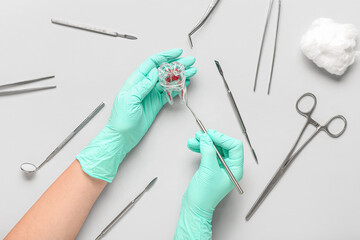 Dentist with plastic tooth and tools on light background, top view
