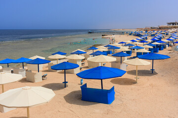 Sun loungers with umbrellas on the beach in Marsa Alam at sunrise, Egypt
