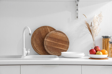 White counters with sink, fruits and wooden boards in interior of modern kitchen