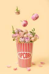 Paper popcorn bucket with beautiful flowers on color background