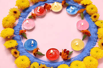 Burning candles with beautiful marigold flowers and colorful powder on pink background. Divaly celebration