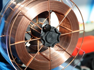 Copper covered welding wire coil on arc machine closeup. MIG MAG welding equipment - obrazy, fototapety, plakaty