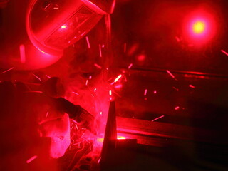 Electric MIG MAG metal welding process in red. Welder man work in welding mask closeup. Gas Metal...