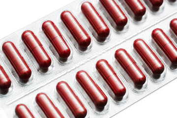 Metal tablet blister. Red pills medicine. Silver shiny blister with drugs. Red color capsules isolated on white. Cutout medicament isolated on white. Aluminum pills blister.