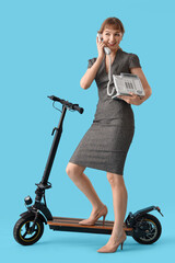 Portrait of young businesswoman with kick scooter and phone on blue background © Pixel-Shot