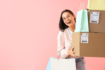 Female seller with shopping bags and boxes on pink background
