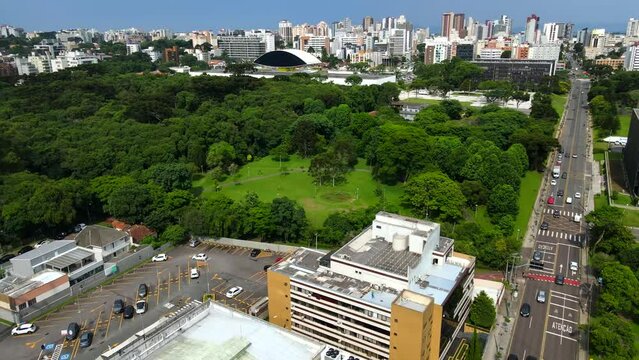 Aerial shot drone flies over large green park toward Oscar Niemeyer Museum