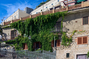 Panoramic landscape view vintage stone house with lush green color ivy. Downtown of Taormina. Travel and tourism concept