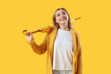 Mature woman with umbrella on yellow background