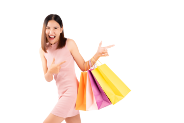 Excited beautiful Asian woman wearing dress hold shopping bags isolated on pink background and copy space Surprise happy asian lady open mouth with excited Beauty young girl pointing to copy space