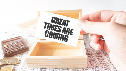 Businessman hold white card with text GREAT TIMES ARE COMING Calculator, wood box, money and financial documents