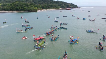 Pangandaran Beach, West Java, Indonesia. A stunning scene where a group of tourists celebrate the beauty of nature while enjoying the hajat laut, an interesting cultural procession.