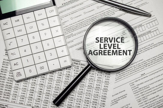 SERVICE LEVEL AGREEMENT word on magnifying glass with calculator and documents