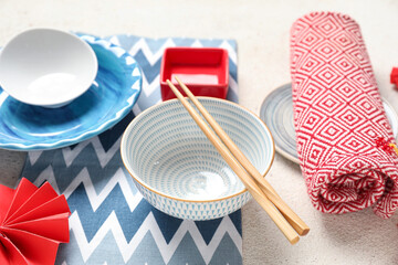 Mat with bowls, chopsticks and decor on white grunge background. Chinese table setting