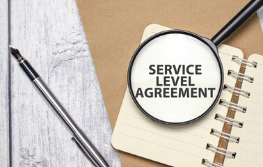 SERVICE LEVEL AGREEMENT words on magnifying glass with pen and papers