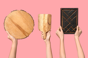 Female hands with wooden cutting boards on pink background
