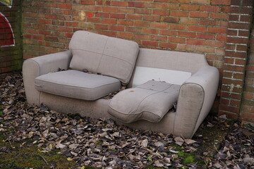 old sofa thrown out on street. illegal dumping of bulk furniture on residential estate. 