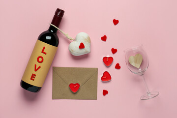 Bottle of wine with glass, envelope and hearts on pink background. Valentine's Day celebration