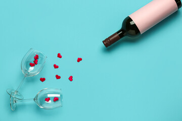 Bottle of wine, glasses and hearts on turquoise background. Valentine's Day celebration