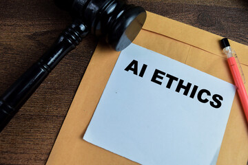 Concept of Ai Ethics write on sticky notes with gavel above brown envelope isolated on Wooden Table.