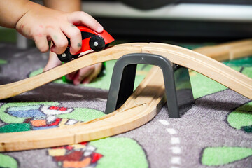Child playing with wooden toy car. Wooden train set with track. Children's playroom 