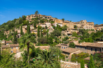 Fototapeta premium Stunning cityscape of the small coastal village of Deia in Mallorca, Spain. Traditional houses terraced on hills surrounded by green trees. Tourist destinations in Spain. Balearic Islands.